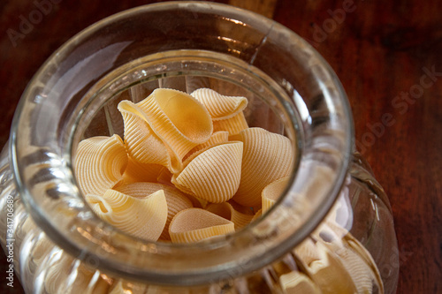 pasta tradizionale conchiglie dentro a grande ciotola di vetro sopra tavolo di legno photo