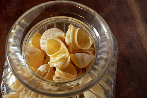 pasta tradizionale conchiglie dentro a grande ciotola di vetro sopra tavolo di legno photo