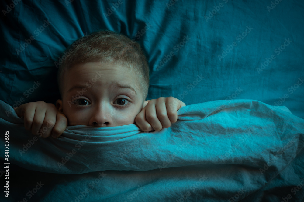 boy in bed with his eyes open. the child is afraid of the dark