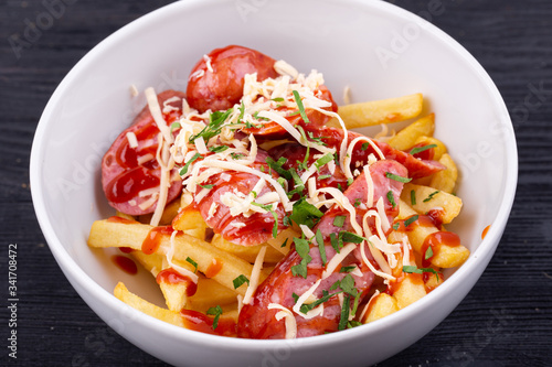 Salad with sausage, grated cheese, potatoes and ketchup with greens
