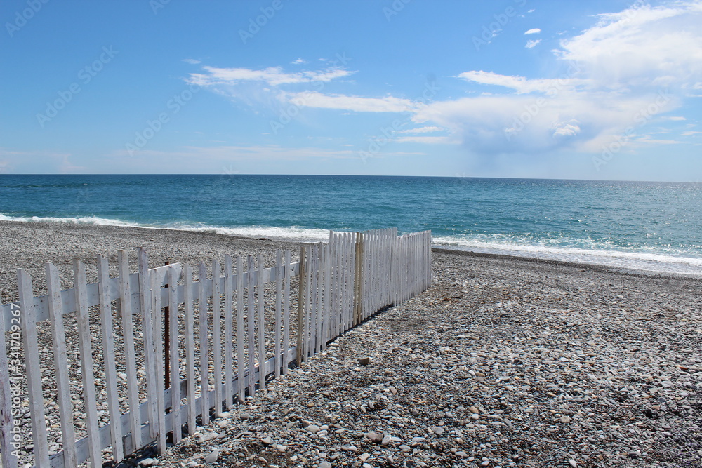 Rocky beach with white, wooden fence near ventimiglia