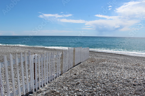 Rocky beach with white  wooden fence near ventimiglia