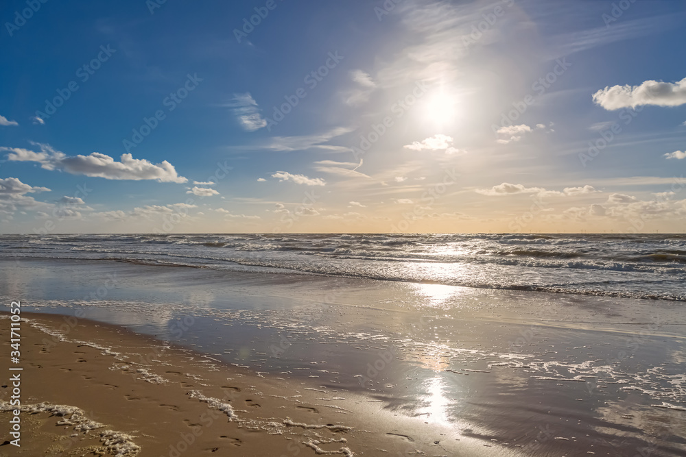 Die Sonne steht über dem Meer und wirft Reflektionen an den Strand
