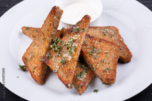 Garlic grens made of black bread, served with greens and cream sauce photo