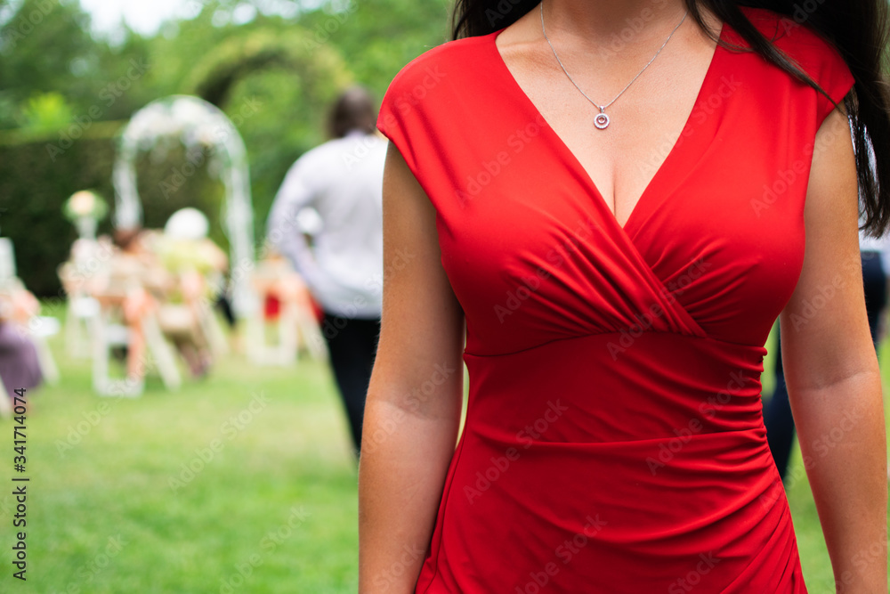 young woman in red dress with sexy neckline on party event with people in background