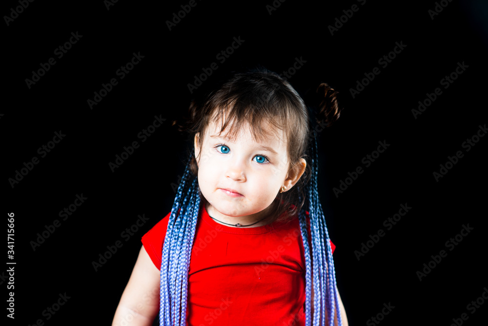 A little girl on a black background with Afro-pigtails, artificial plaited in elastic bands and put on A little girl on a black background with Afro-pigtails, artificial plaited in elastic bands and put on