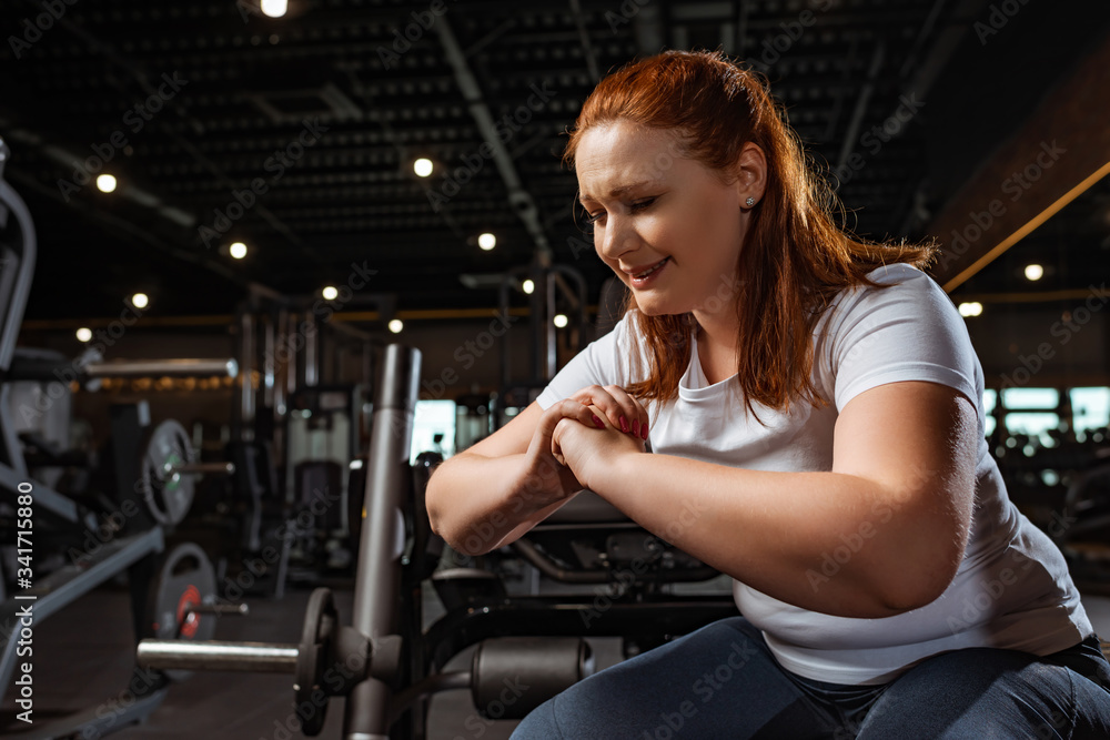 overweight girl frowning while squatting with clenched hands overweight girl frowning while squatting with clenched hands