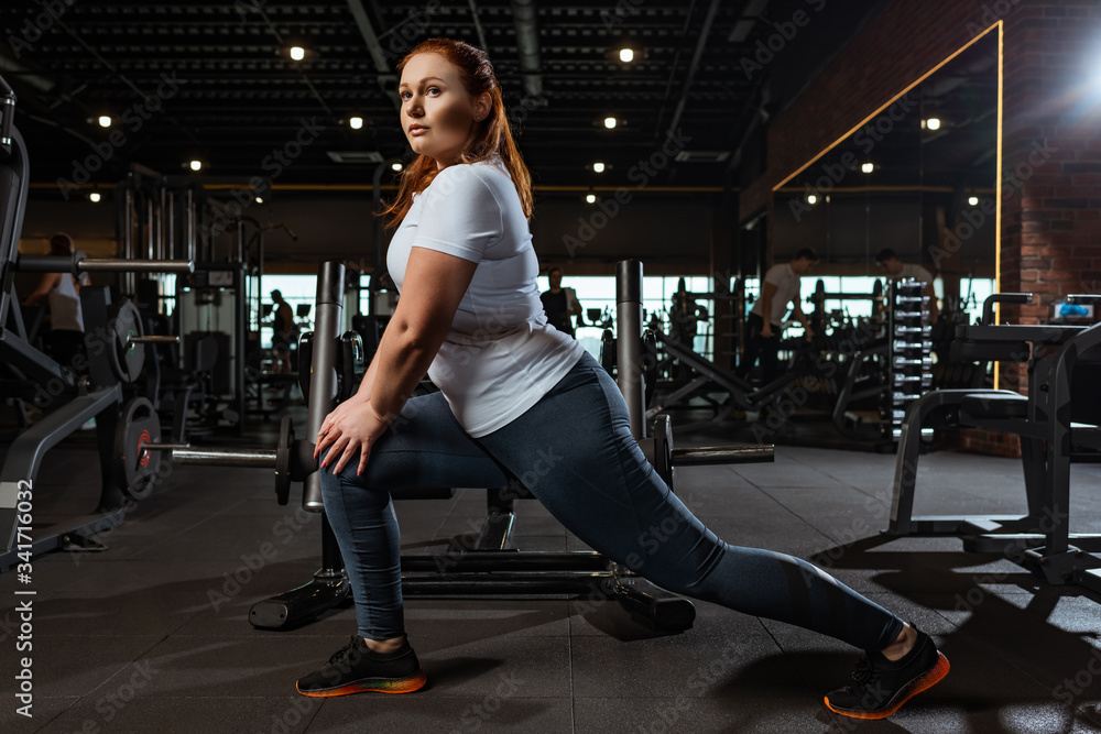 pretty, overweight girl doing lounges exercise in gym