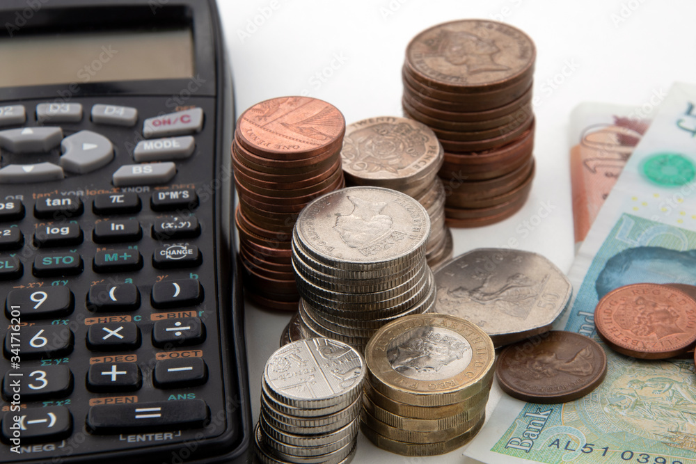 Piles of coins and some British bank notes with black calculator Piles of coins and some British bank notes with black calculator