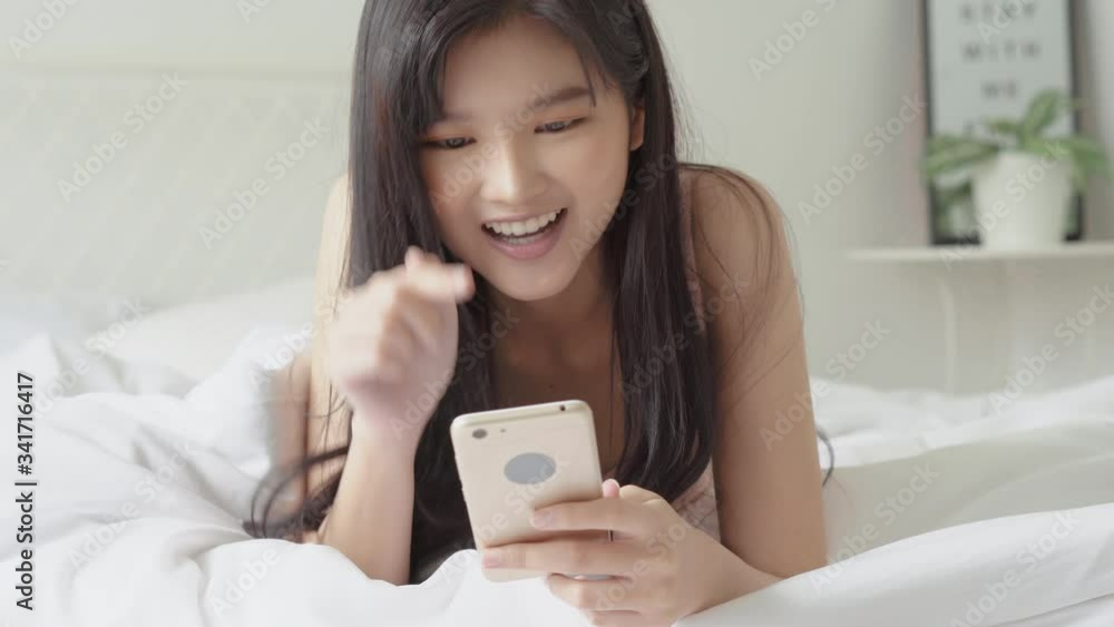 Beautiful young asian woman looking and touching smart mobile phone relax enjoy with social network on bed at bedroom, girl chat messaging to internet online, communication concept. Beautiful young asian woman looking and touching smart mobile phone relax enjoy with social network on bed at bedroom, girl chat messaging to internet online, communication concept.
