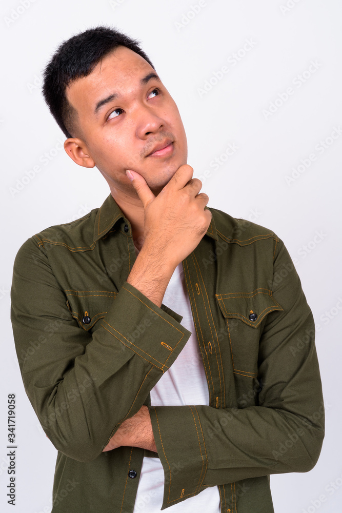 Portrait of young Asian man thinking and looking up Portrait of young Asian man thinking and looking up