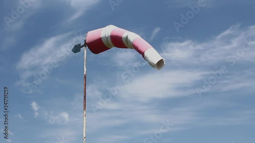 Windsock, red and white pointer is indicating strength and direction of the wind against cloudy sky.
