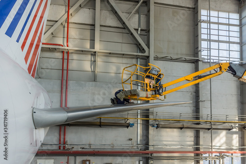 A boom lift taking a worker to the plane tail. Aircraft maintenance service photo