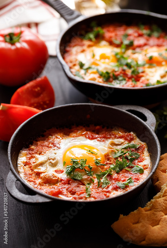 Shakshuka a traditional dish of tomato, eggs and peppers with the addition of aromatic spices in a cast iron dish close up