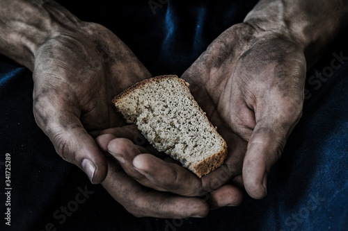 dirty men's hands with a piece of bread, poverty, hunger