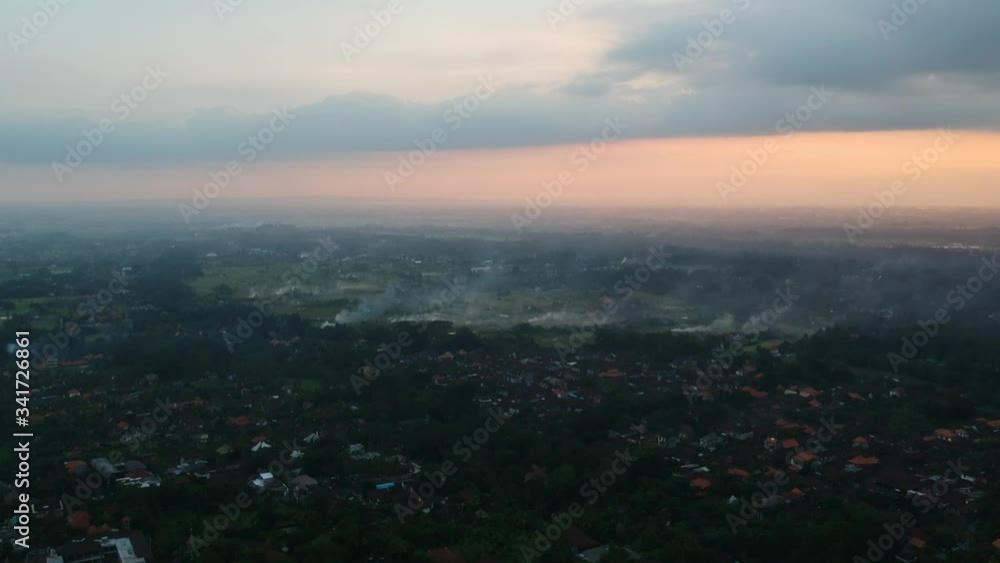 quadrocopter flies over the jungle of Ubud in Bali, fires with smoke are visible, and flies to sunset, the whole sky is in clouds and the yellow-orange sun is visible in the evening quadrocopter flies over the jungle of Ubud in Bali, fires with smoke are visible, and flies to sunset, the whole sky is in clouds and the yellow-orange sun is visible in the evening