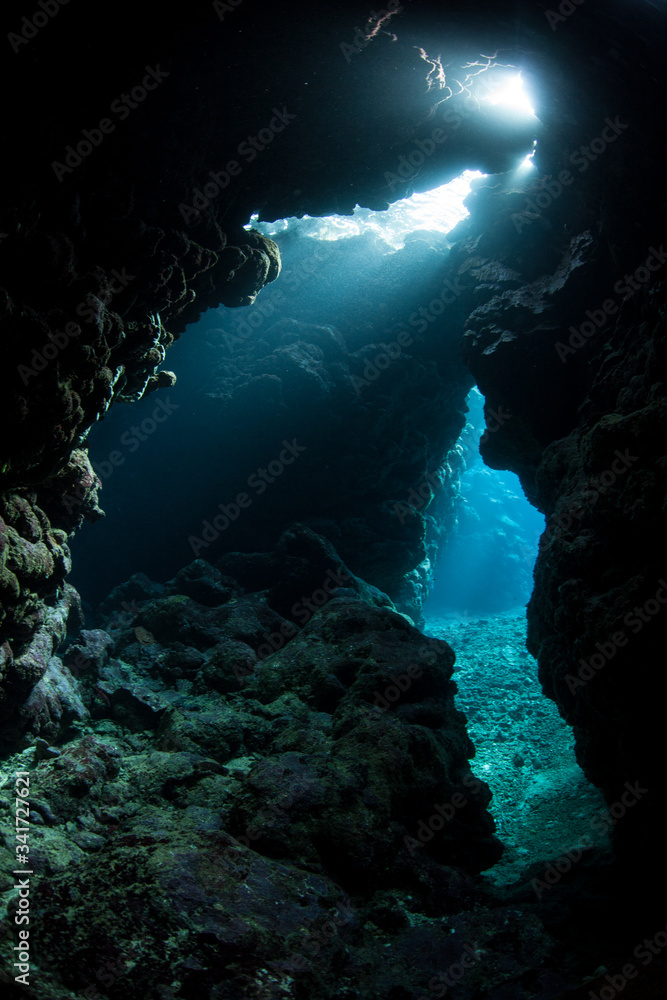 Light seeps into a dark, underwater cavern in the tropical Pacific Ocean. Caves and caverns riddle coral reefs and limestone islands.