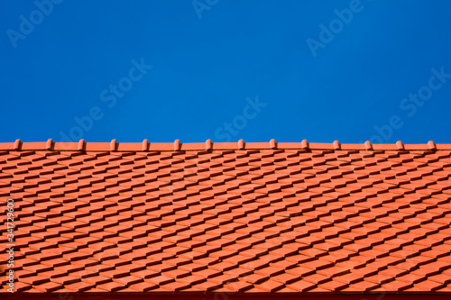 Low angle view of red tiles roof slope in horizontal pattern against blue clear sky in sunny day, exterior architecture concept 