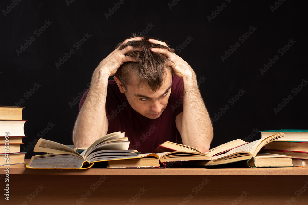 a young man sits at a table holding his hands behind his head. problems at work. office employee. a young man sits at a table holding his hands behind his head. problems at work. office employee.