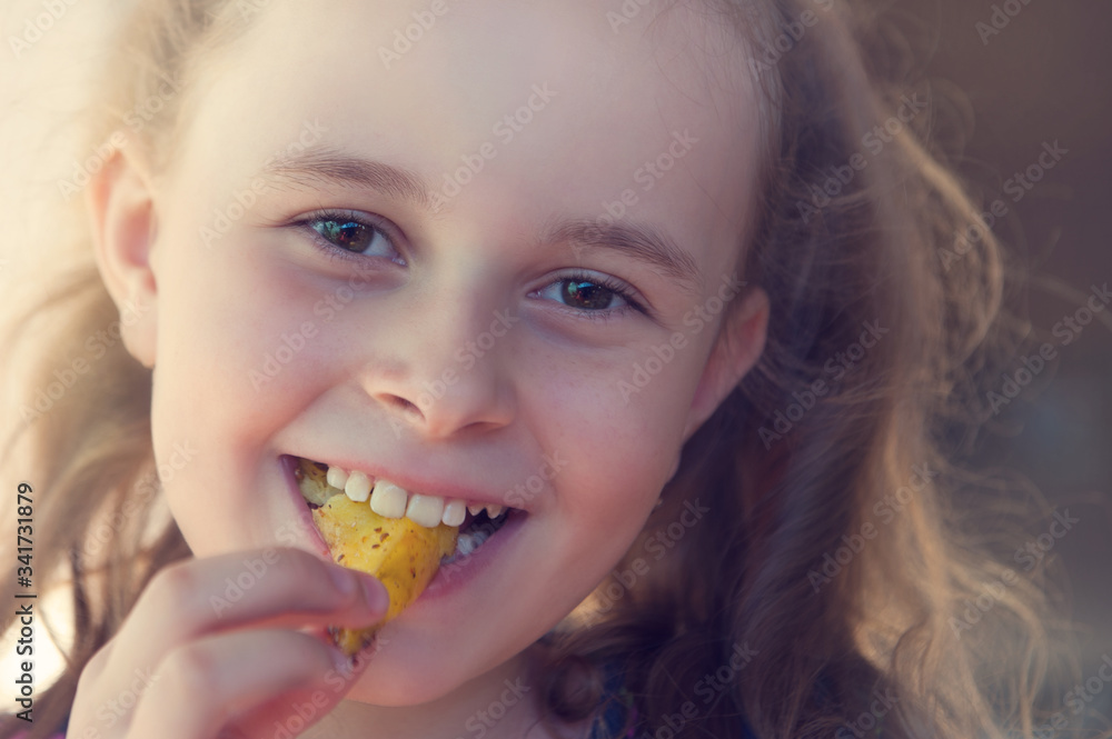 Closeup portrait of a blond girl eating fried potatoes. Smiling child outdoors Closeup portrait of a blond girl eating fried potatoes. Smiling child outdoors