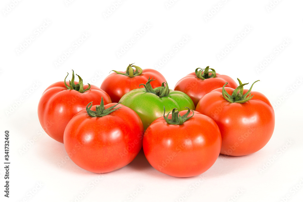 Group of red fresh tomatoes and one green tomate on a white background Group of red fresh tomatoes and one green tomate on a white background