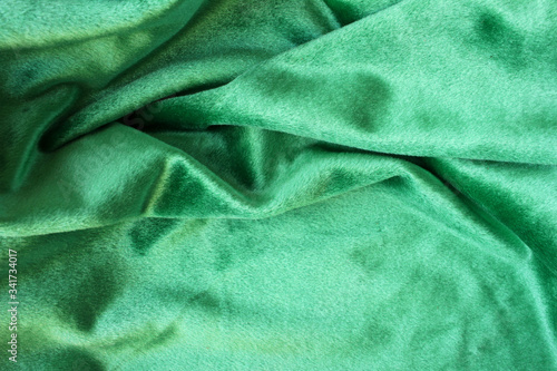 Green velour fabric texture. Wavy folds background. Fragment of a drapery dark green cloth material 