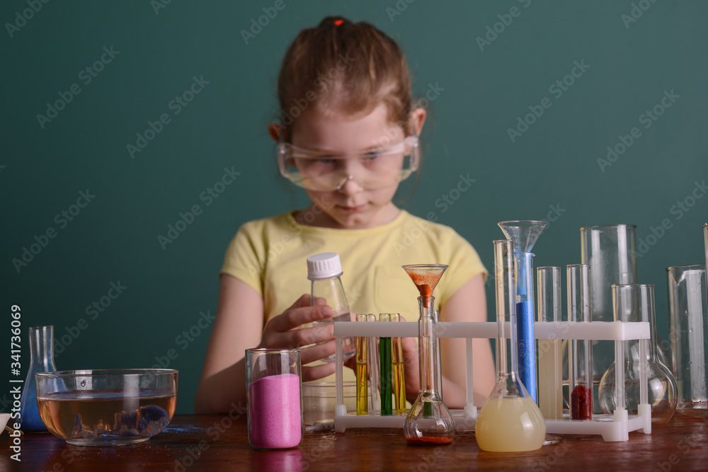 girl in safety glasses at home doing experiments with chemicals. school experiments at home. girl in safety glasses at home doing experiments with chemicals. school experiments at home.