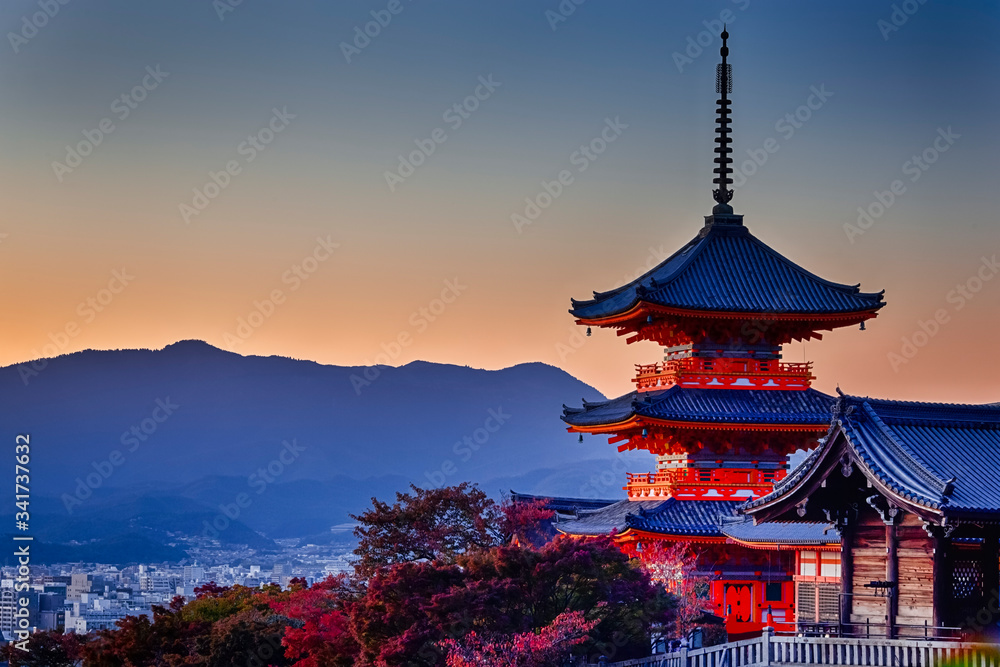 Fototapeta premium Dziedzictwo japońskie. Żywy zachód słońca nad pagodą świątyni Kiyomizu-dera z tradycyjnymi czerwonymi klonami w tle w Kioto w Japonii.