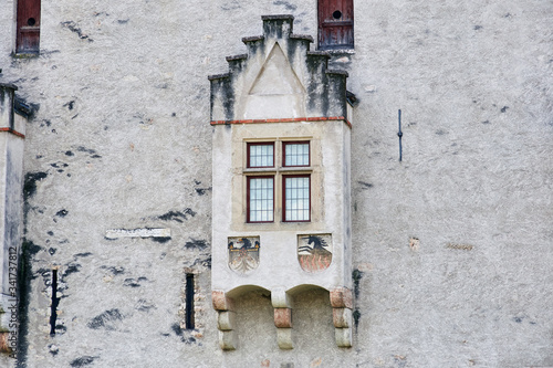 Italian window on the old castle wall facade with wooden red color frame