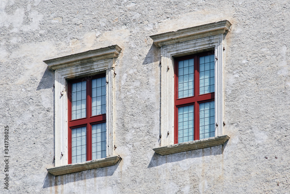 Two Italian windows on the old castle wall facade with wooden red color frame