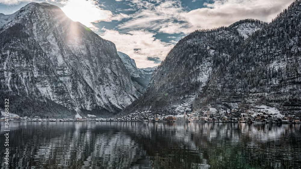 Fototapeta premium Snowy village Hallstatt at the foot of mountain with sun light in winter in Austria