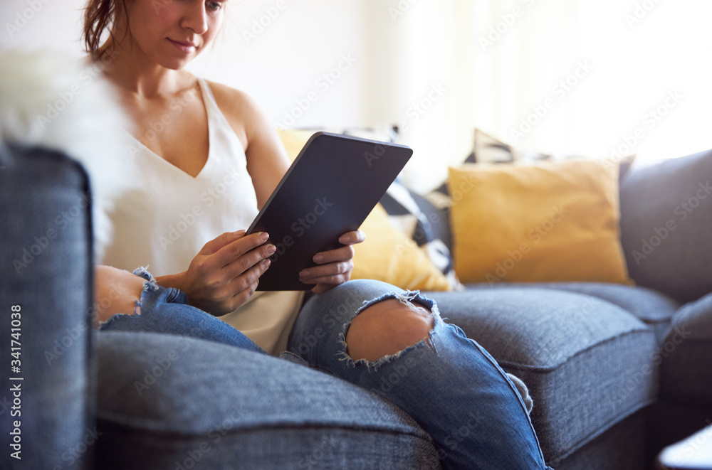 Young female working on tablet computer sat on sofa Young female working on tablet computer sat on sofa