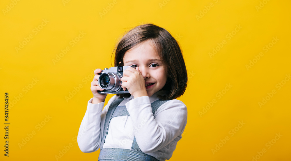 Girl using a photo camera on yellow background Girl using a photo camera on yellow background