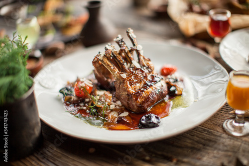 Quadro su tela Plate with grilled ribs with sauce haute cuisine on wooden table in daylight res