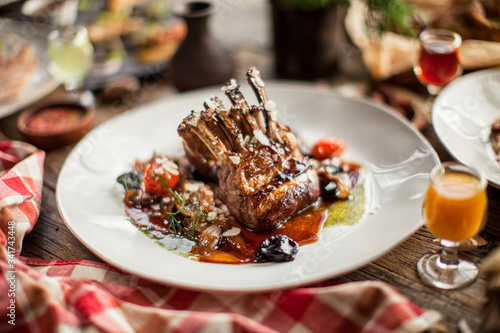 Quadro su tela Plate with grilled ribs with sauce haute cuisine on wooden table in daylight res