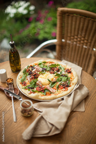 Italian pizza with towel and olive oil on wooden table cafe restaurant at terrace bokeh