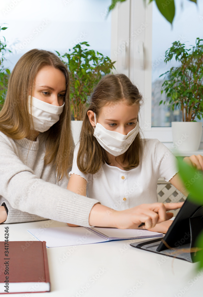 Schoolgirl with her mother at distance learning. Home schooling concept.