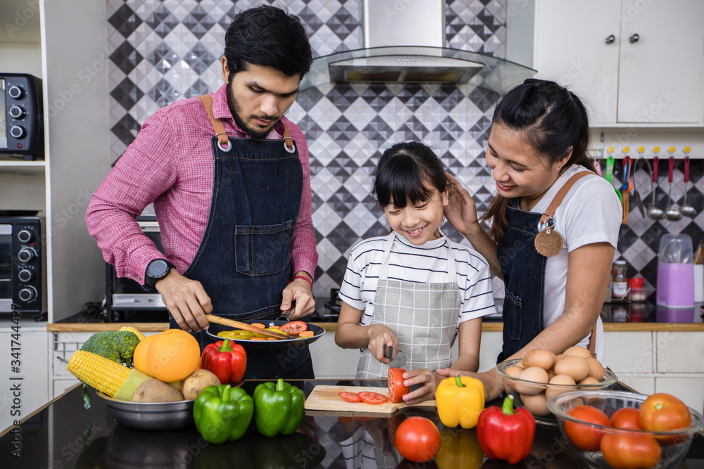 Asian families are cooking and parents are teaching their daughters to cook in the kitchen at home. .Family activities on holidays and Happy in recreation concept Asian families are cooking and parents are teaching their daughters to cook in the kitchen at home. .Family activities on holidays and Happy in recreation concept