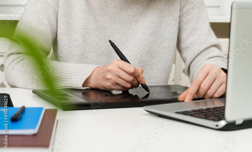 Female designer using graphic tablet at home.
