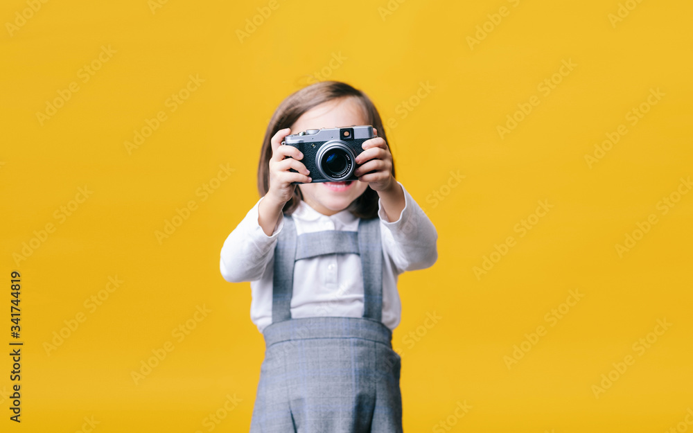 Girl using a photo camera on yellow background Girl using a photo camera on yellow background