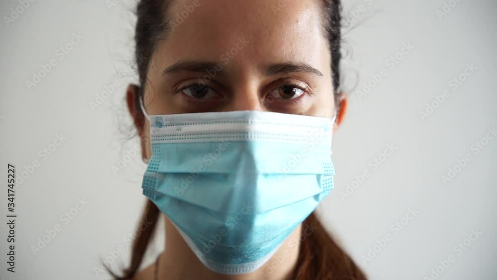Beautiful young woman while opens his eyes wearing a medical mask of protection from the Coronavirus, Covid-19 - Millennial protects herself from the infection by wearing personal protection tools