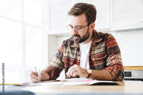 Portrait of young bearded man working with notes at home