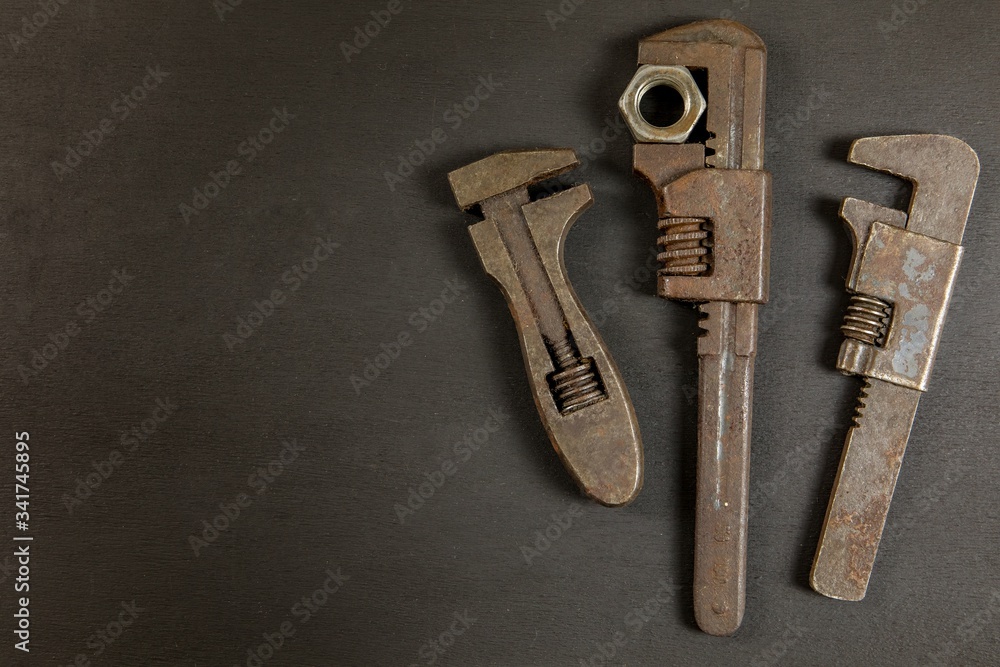 Old rusty wrench on black background, top view. Old dirty tools. Handmade. Household repairs. Old rusty wrench on black background, top view. Old dirty tools. Handmade. Household repairs.