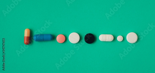 multi colored pills in a row on a green background