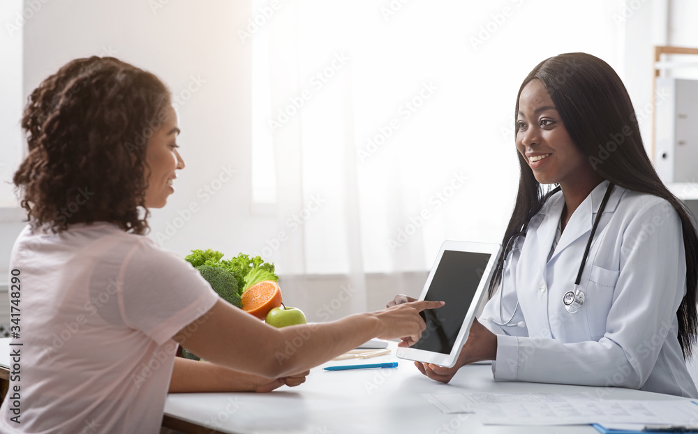 Woman nutritionist using digital tablet in office, making patient's anamnesis Woman nutritionist using digital tablet in office, making patient's anamnesis
