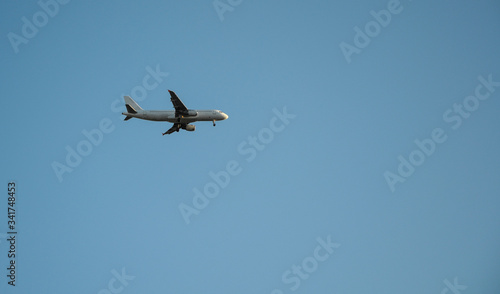 Passenger jet plane flying through blue sky with no clouds. Travel flight for vacation. Aviation transport 