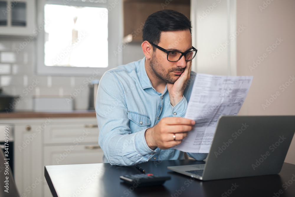 A young businessman working from home holding piece of paper. A young businessman working from home holding piece of paper.