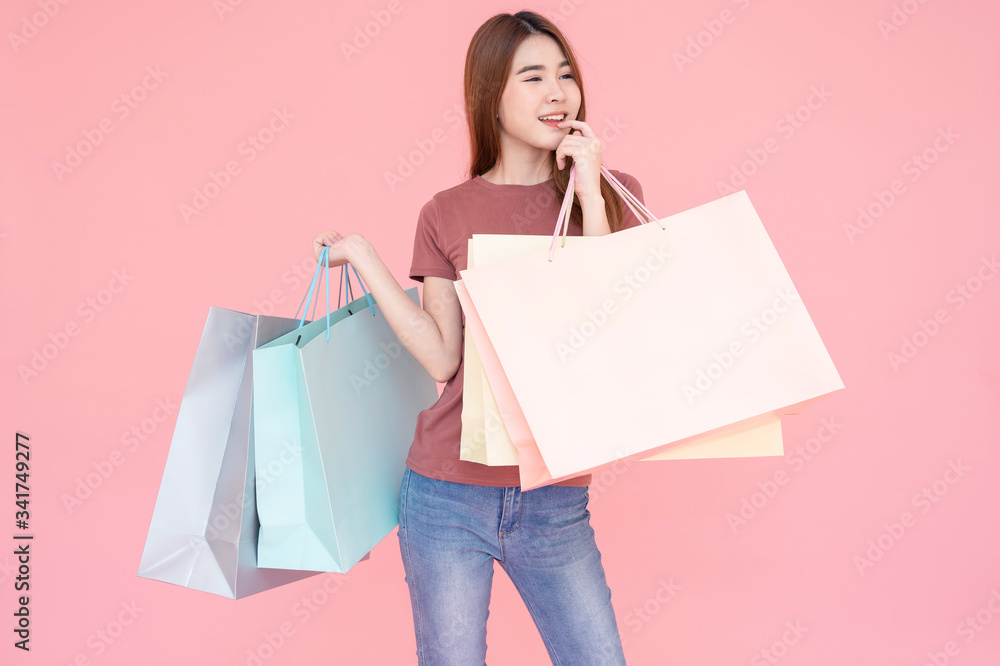 Portrait of Beautiful young smiling happy woman holding shopping bags isolated pink background Portrait of Beautiful young smiling happy woman holding shopping bags isolated pink background