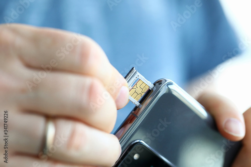 Male hands getting sim card slot of his smartphone out photo