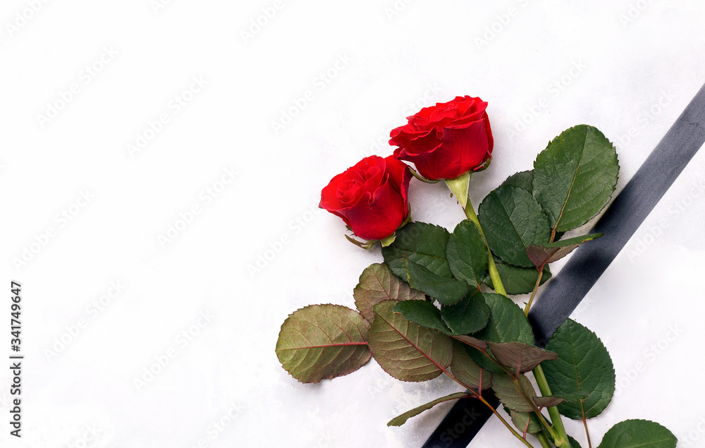 The concept of death and mourning. Fresh rose flowers with black mourning ribbon on a white background